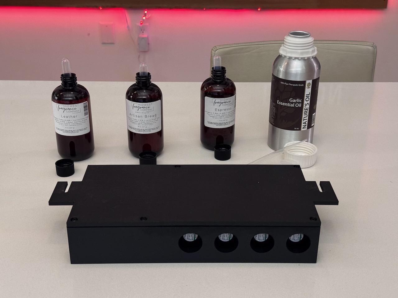 Photo of the device, fully assembled, with four oil jars behind it Oiling up